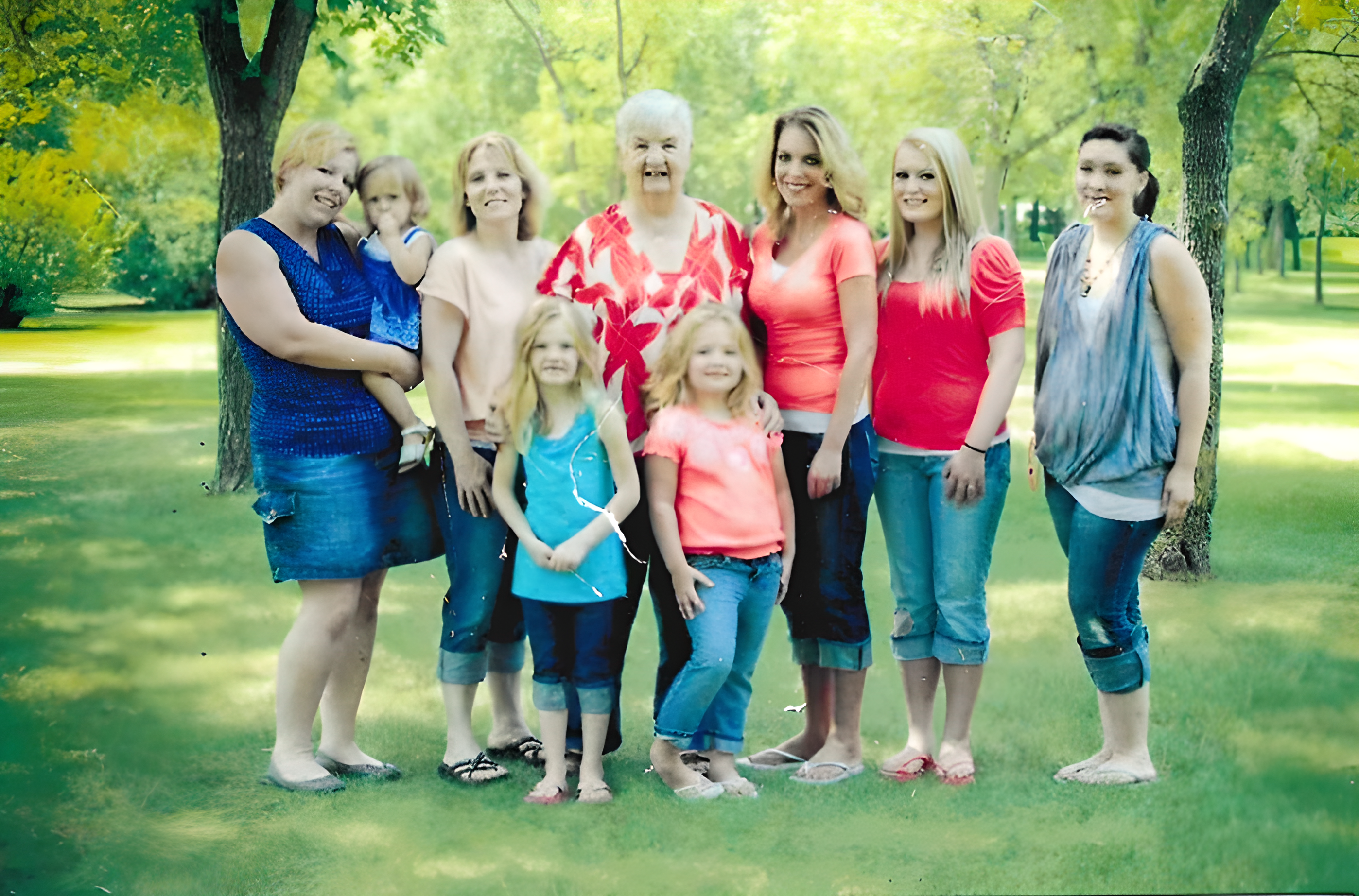 A multi-generational family posing outdoors in casual summer attire.
